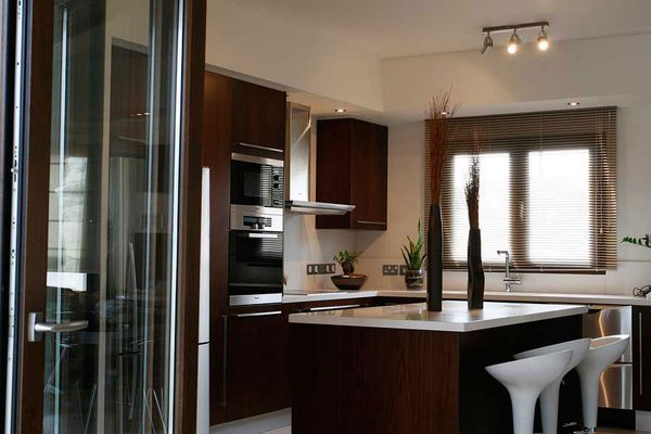 Glazed door opening onto a kitchen with dark timber units