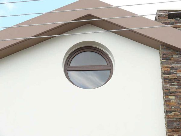 Round window set in a rendered gable above stone cladding